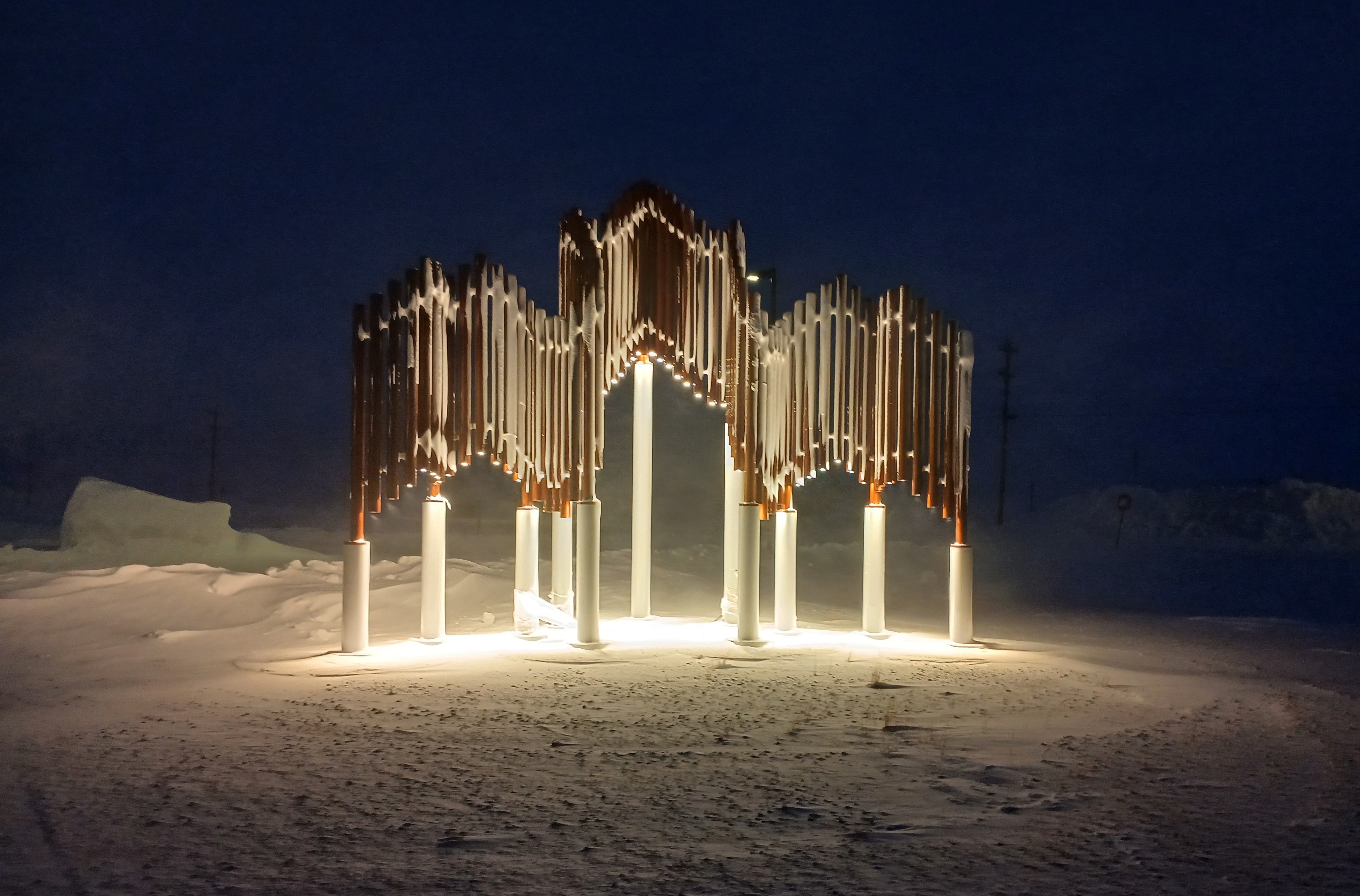 Photo of large art piece standing in snow made with vertical pipes that form a three-dimensional stylized maple leaf used in the design of the POLAR Star.